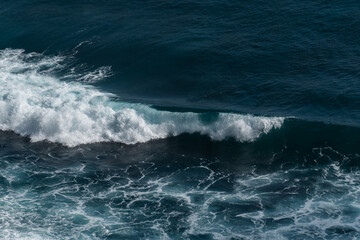 The waves of the ocean water meet with underwater pointed rocks