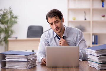 Young male employee and too much work in the office