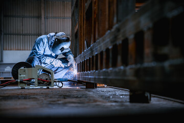 Industrial welder welding fabricated construction in factory, Welding process by Flux Core Welding,...