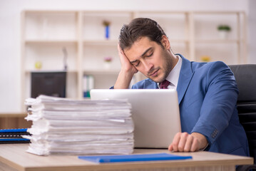 Obraz premium Young male employee and too much work in the office