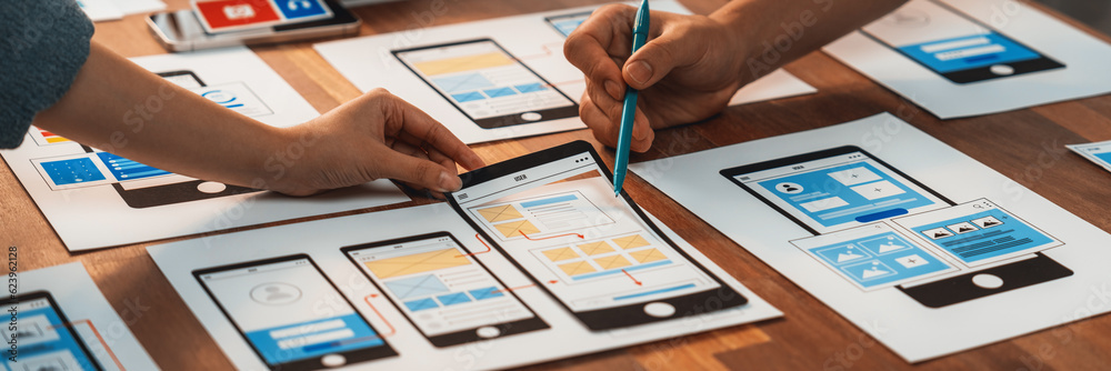 Poster Panorama shot of front-end developer team brainstorming UI and UX designs for mobile app on paper wireframe interface. User interface development team planning for user-friendly UI design. Scrutinize