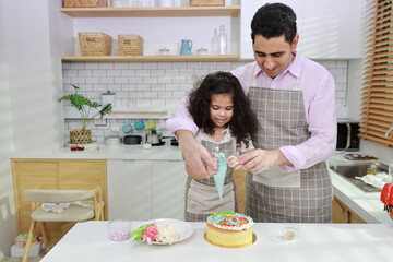 Obraz na płótnie Canvas Happy lovely asian single dad and cute daughter in apron having fun with teaching and decorating homemade cake in the kitchen. Family lifestyle cooking with education concept.