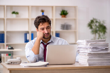 Young male employee and too much work in the office