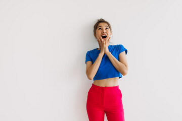 Shocked and surprised asian woman looking up at empty space isolated on white.