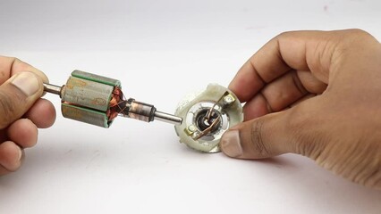 DC motor rotor with copper commutator and coil wire winding along with carbon brush held in the hand
