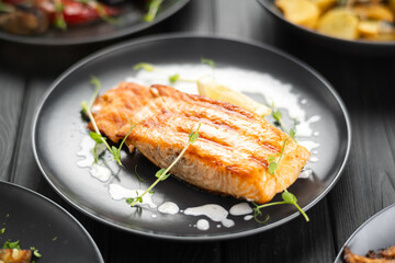 Gourmet portion of thick juicy fresh salmon grilling on with lemon on wooden table, copy space