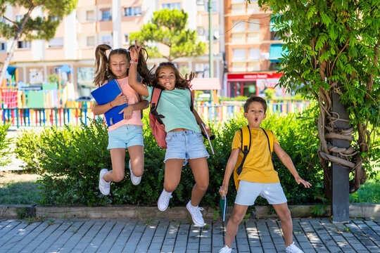 Back To School. Group Of 3 School Children With Backpacks. Children Are Happy And Ready To Learn. Positive Cheerful And Active Jumps. Smiling And Happy School Kids Jumping. Edcucation