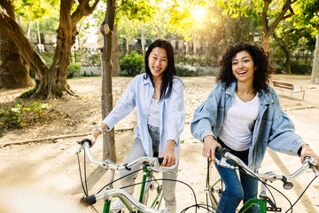 Young group of women enjoying summer vacation riding bicycles while sightseeing. Millennial group...