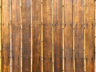 Wooden wall with beautiful patterned bamboo on brown wooden background.