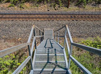 Metal stairs lead downward to railroad tracks