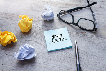 Message on Brain Dump is written on the Post-it Notes on the wooden table 