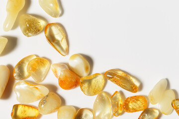 Amber stones at sunlight on light background, transparent stone yellow beige color. Natural gemstone mineral material, healing crystal. Top view Amber texture. Nature gems, frame