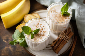 Detox menu. Banana smoothie with cinnamon in drinking glass on a wooden background.