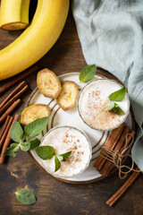 Banana smoothie with cinnamon in drinking glass on a wooden background. Detox menu. View from above.