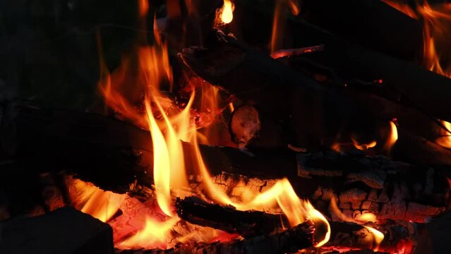 Close-up, flames from fire. Night bonfire, logs are on fire, sparks fly. 4k horizontal slow motion footage. Burning branches tongues of flame. Hiking, Tourism, Travel. Lifestyle Go Everywhere concept