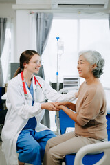 Friendly Female Head Nurse Making Rounds does Checkup on Patient Resting in Bed. She Checks tablet while Man Fully Recovering after Successful Surgery in hospital.