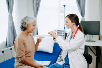 Obraz premium Friendly Female Head Nurse Making Rounds does Checkup on Patient Resting in Bed. She Checks tablet while Man Fully Recovering after Successful Surgery in hospital.
