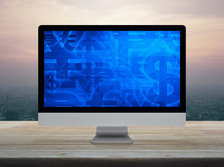 Financial currency symbol on desktop computer monitor screen on wooden table over city tower and skyscraper at sunset sky, vintage style