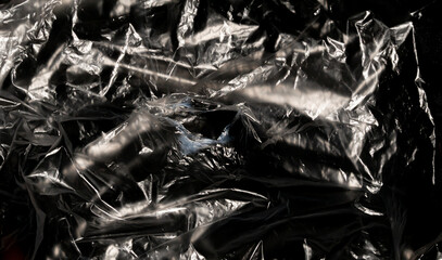 Close-up shot, crumpled plastic on black background. Environment, global warming conservation and warning signs