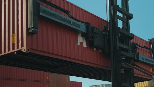 4K actual cam shooting of heavy duty forklift lifting container to place it by other stacked cargo at commercial port area stock video.