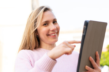 Young blonde woman holding a tablet at outdoors