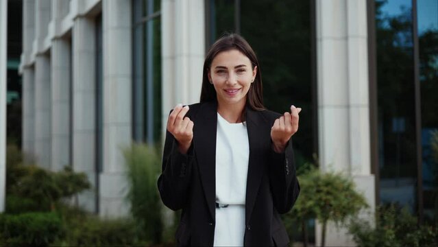 Beautiful young business woman smile rubbing fingers show cash gesture, Come Give Me Money. Beautiful lady demanding money looking at camera with Pay Me Profit sign outdoor.