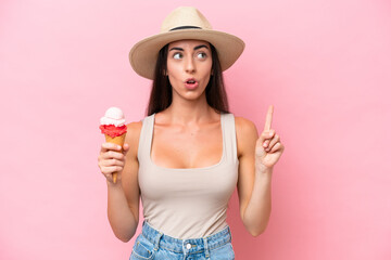 Young caucasian woman with a cornet ice cream isolated on pink background thinking an idea pointing...
