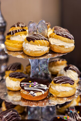 profiterole and eclairs with wiped cream and glazed with chocolate and fondant , kids birthday party, on a shiny display table