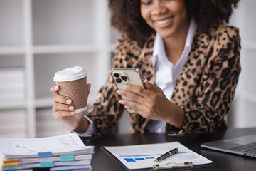 Young African American businesswoman working with smartphone  and laptop at desk in office, business finance technology concept.