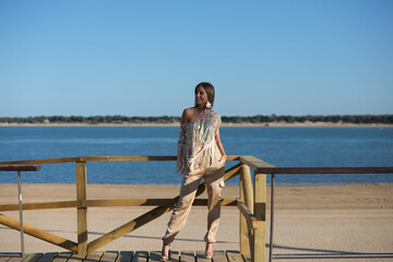 Beautiful young blonde woman walks along the promenade on the south coast of spain in Sanlucar de barrameda, city of wine and gastronomy, in the background the mouth of the river guadalquivir.