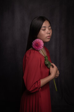 classic art portrait of an asian woman in red dress holding pink dahlia flower