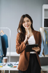 Smiling female fashion designer with tablet , looking to camera.