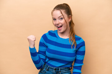 Young caucasian woman isolated on beige background celebrating a victory