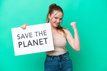 Young caucasian woman isolated on green background holding a placard with text Save the Planet and doing strong gesture