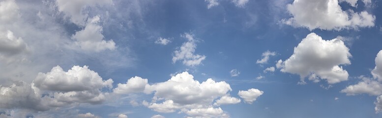 Naklejka na ściany i meble white fluffy clouds in the blue sky in sunny summer day. panoramic image.