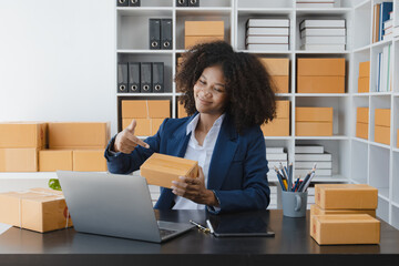 African American owner checking orders from customers sitting at desk in office, sell products online concept.