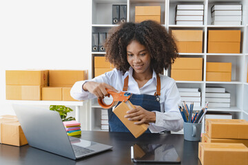 African American owner checking orders from customers sitting at desk in office, sell products online concept.