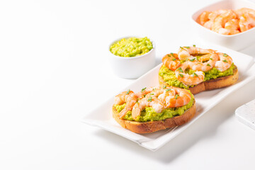 Appetizer toasted bruschetta with mashed avocado and shrimps on background. Healthy food concept with prawns.