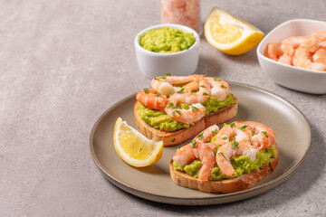 Appetizer toasted bruschetta with mashed avocado and shrimps on background. Healthy food concept with prawns.