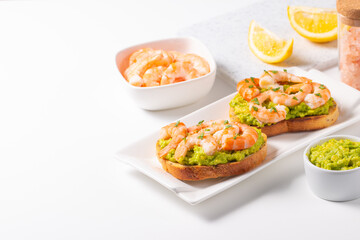 Appetizer toasted bruschetta with mashed avocado and shrimps on background. Healthy food concept with prawns.