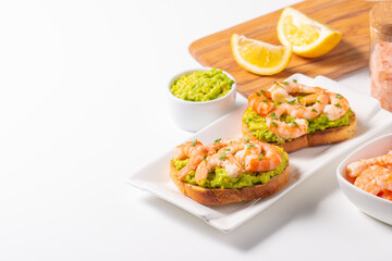 Appetizer toasted bruschetta with mashed avocado and shrimps on background. Healthy food concept with prawns.