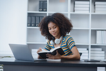 Young African American woman with wearing headphones and laptop at desk in office, Online education, Young African American.