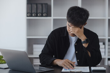 Asian businessman working online with laptop are stressed and tired from work sitting at desk in the office, feeling sick at work, stress from work.	