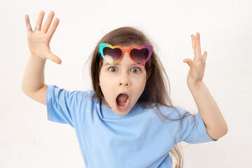 Portrait of surprised cute little toddler girl in the heart shape sunglasses. Child with open mouth having fun isolated over white background. Looking at camera. Wow funny face