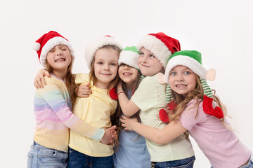 Merry Christmas and Happy New Year! A group of cheerful happy children in festive santa claus and elf hats on a white studio background. Children hug and have fun