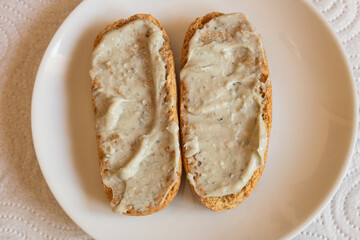 Overhead view of toasted wholemeal rolls spread with Cabrales cheese cream on a plate, accompanied by a napkin as a background.  Combination of flavors and textures in traditional Spanish dishes.