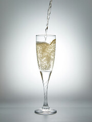 Pouring champagne into a glass on a gray background.