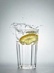 Lemon splashing in a glass of water