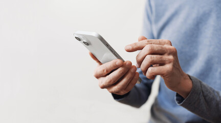 Closeup of adult male hand using mobile phone, Young man texting on smartphone over grey background