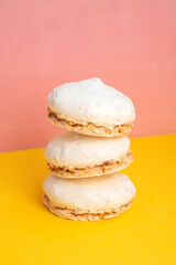 Sweet meringue dessert on a pink yellow background. Floating crispy round cakes, levitation concept. Cookie building.